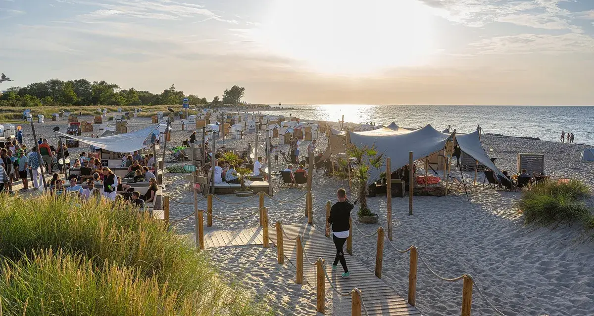 Sommerliche Ostsee Party mit vielen Gästen, Strandkörben und Zelten am Abend.
