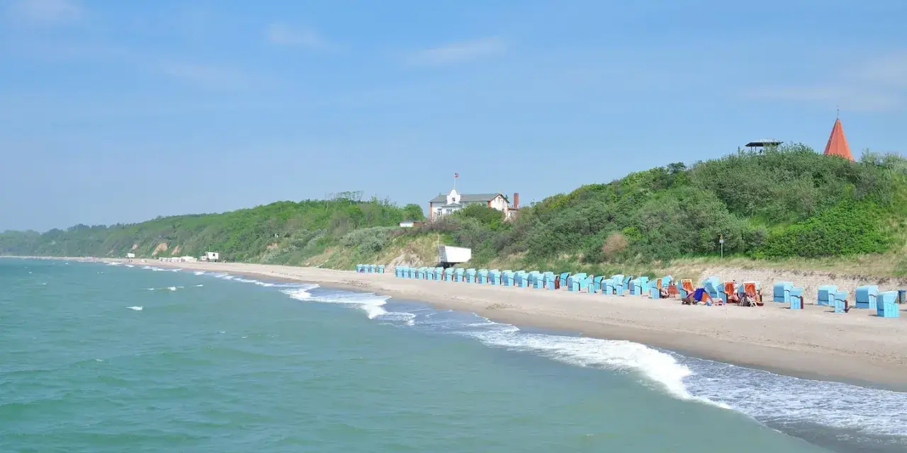 Strand mit Strandkörben und grünen Hügeln. Hier finden Sie Rerik Geheimtipps für einen entspannten Urlaub an der Ostsee.