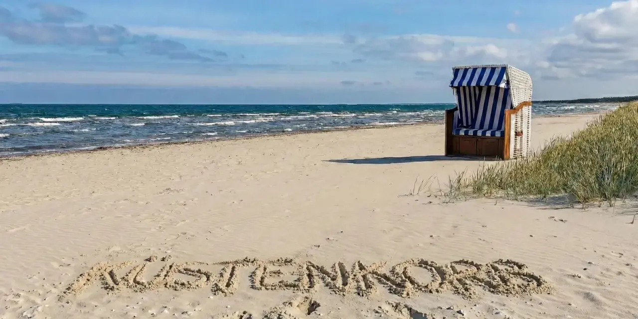 Der Juliusruh Strand lädt mit einer Strandmuschel und dem Schriftzug "KUSTENKORS" im Sand zum Verweilen ein.