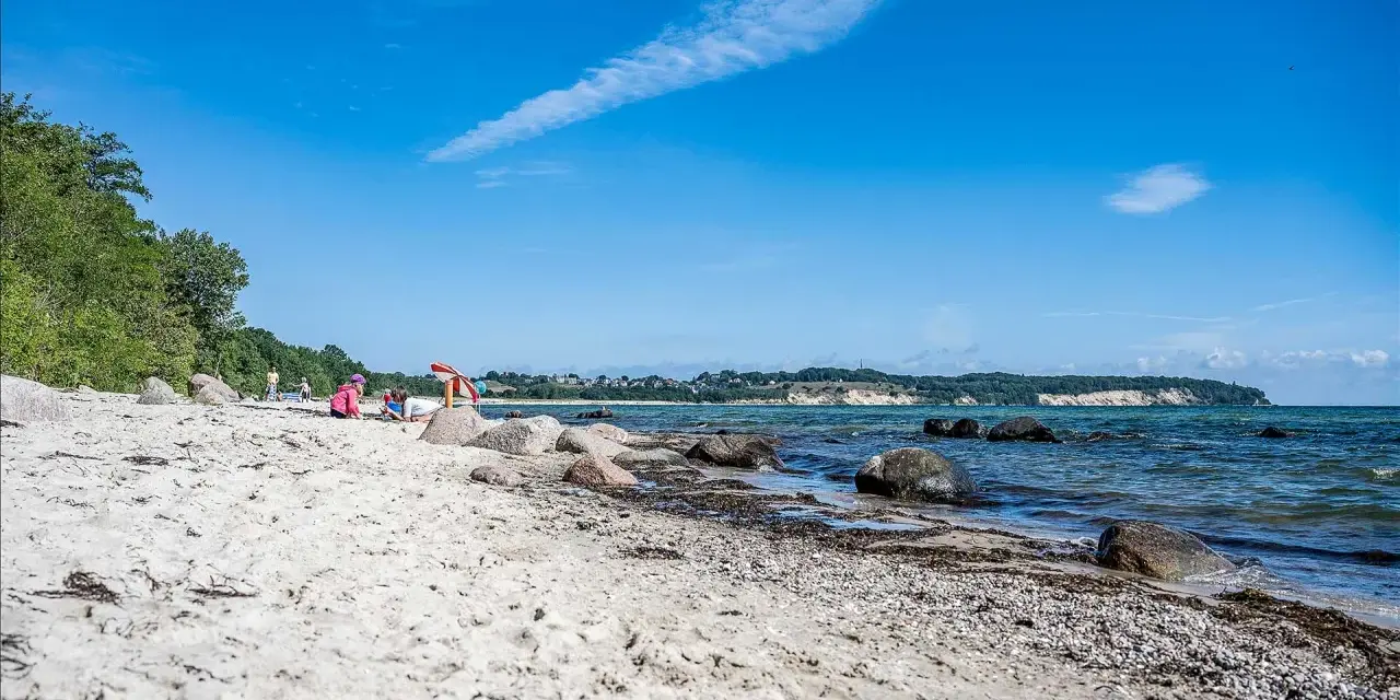 Kinder spielen am lobbe strand. Sand, Steine und das Meer bilden eine idyllische Szene unter blauem Himmel.