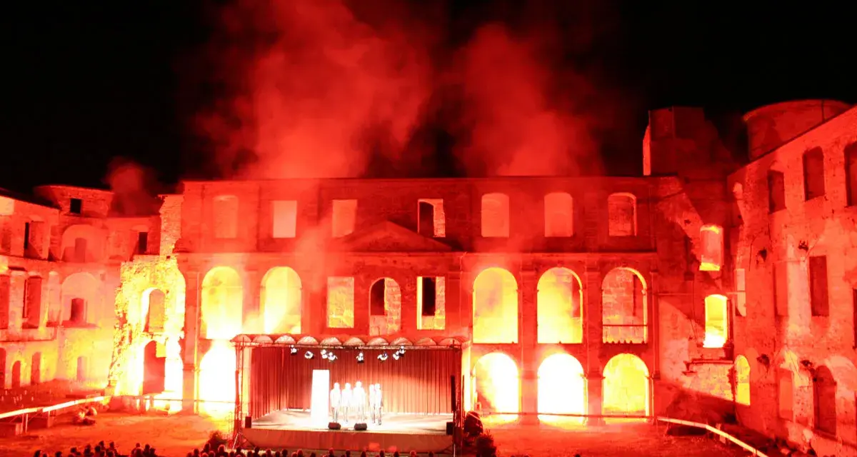 Spektakuläre Inszenierung im Schloss Dargun: Eine Bühne vor der Ruine, beleuchtet von rotem Licht und Nebel, lockt ein großes Publikum zu den Veranstaltungen.