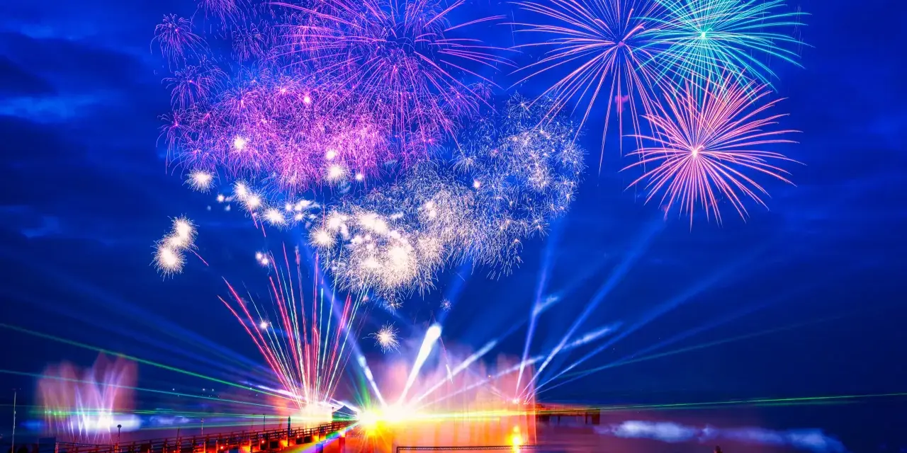 Spektakuläres Feuerwerk und Lichtshow an der Ostsee. Menschen feiern Silvester mit einer ausgelassenen Party am Strand.