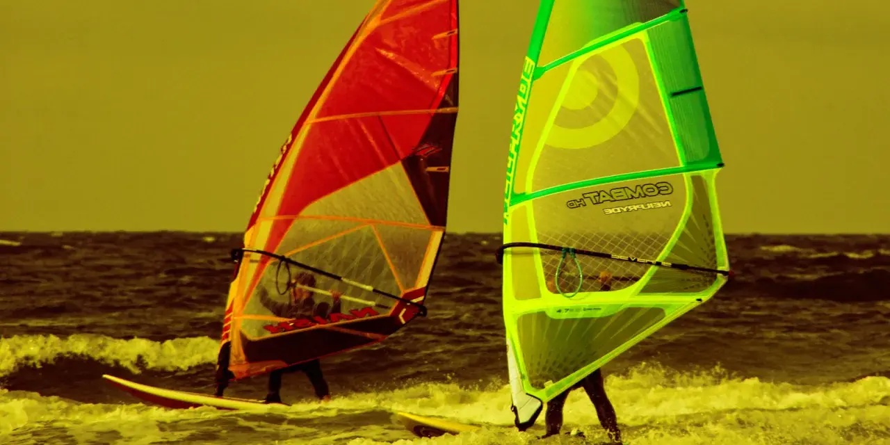 Zwei Windsurfer mit bunten Segeln auf dem Meer. Ein tolles Erlebnis für Surf und Segel Hiddensee.