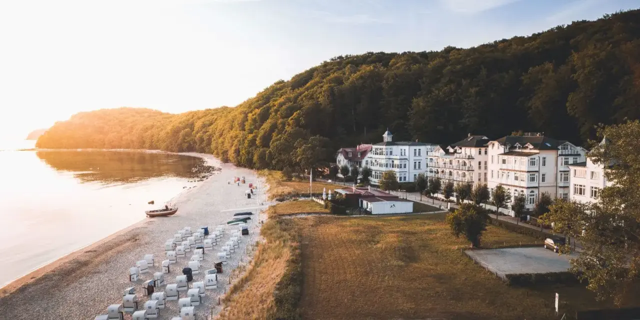 Sonnenuntergang am Binz Strand mit vielen Strandkörben, weißen Villen und einem dichten Wald.