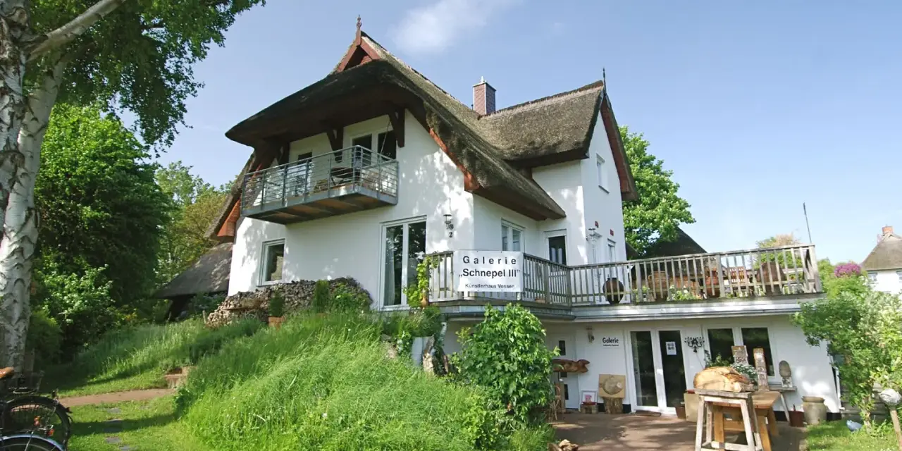 Galerie "Schnepel III" mit Kunsthandwerk und Veranstaltungen. Ein charmantes Haus mit Reetdach und Balkon.