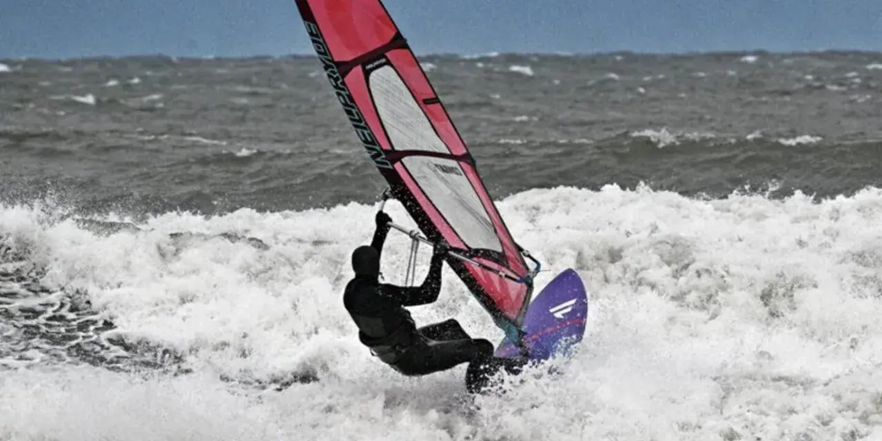 Windsurferin in Aktion auf der Ostsee, die mit ihrem Segel über die Wellen springt.