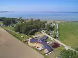 Luftaufnahme des pepelow campingplatzes mit Wohnmobilen, Bäumen und einem See im Hintergrund.