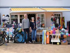 Ein Paar vor einem Laden mit Strandartikeln. Sie sind bereit, juliusruh einkaufen zu gehen und haben alles für einen schönen Tag am Meer.