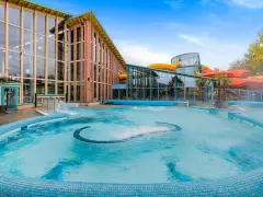 Einladende Therme an der Ostsee mit großem Pool und bunten Wasserrutschen im Hintergrund.