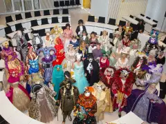 Eine Gruppe in prächtigen Kostümen und Masken, die an venezianische Tage in Schwerin erinnert, versammelt sich in einem modernen Sitzungssaal.