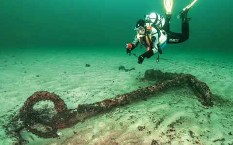 Taucher erkundet ein altes Ankerwrack in der Ostsee.