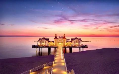 Pier mit beleuchtetem Gebäude im Abendrot, ein romantischer Blick auf die Sellin Innenstadt.