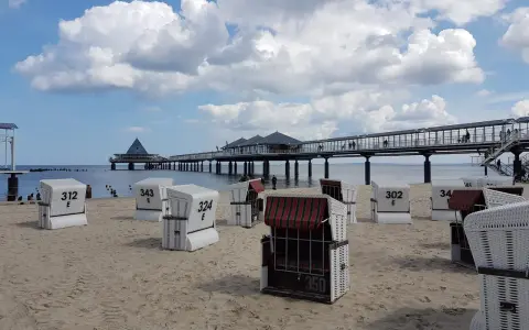Strandkörbe am Zirchow Strand, mit Seebrücke und Wolkenhimmel.