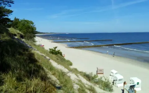 Sonniger Strand Zempin mit Dünen, Wellenbrechern und Strandkörben.