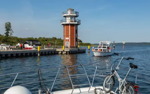Plau am See: Leuchtturm und Promenade mit Booten. Ein Fahrrad wartet auf dem Vorderdeck.