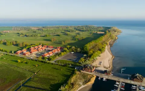 Ferienhäuser am Meer, daneben ein Golfplatz. Ein kleiner Hafen mit Booten.