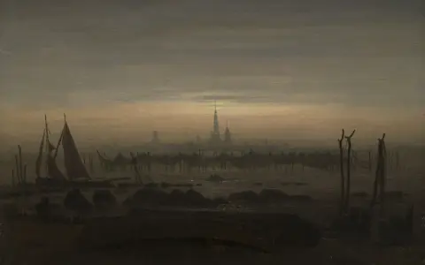 Dämmerung über einer Stadt mit Segelschiffen im Vordergrund, ein typisches Motiv einer Caspar David Friedrich Ausstellung.