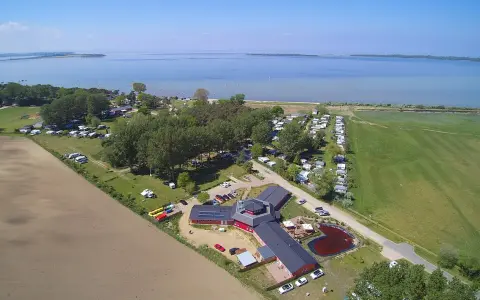 Luftaufnahme des pepelow campingplatzes mit Wohnmobilen, Bäumen und einem See im Hintergrund.