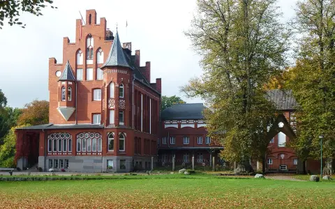 Das imposante Schloss Kalkhorst, ein Backsteinbau mit Türmchen und Erkern, steht im Herbstlicht.