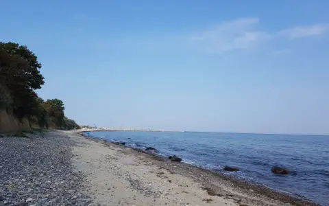 Ein ruhiger Tag am Wittenbeck Strand. Kies und Sand treffen auf das sanfte Meer, im Hintergrund eine Marina.