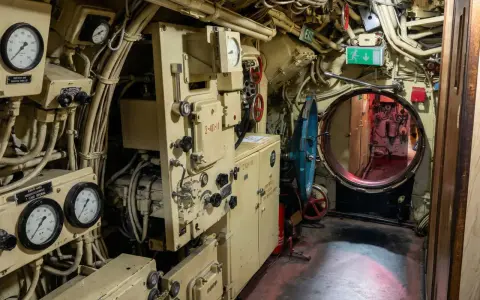Blick in das Innere des U-Bootes U 461. Messinstrumente, Rohre und ein Notausgangsschild sind zu sehen.