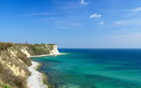 Türkisblaues Meer und Kreidefelsen am Kap Arkona. Ein Leuchtturm wacht über die Küste.