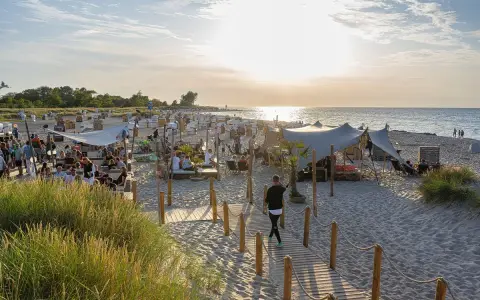 Sommerliche Ostsee Party mit vielen Gästen, Strandkörben und Zelten am Abend.