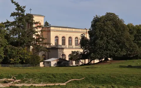 Prachtvolles Gebäude in der **Putbus Altstadt** mit Kirchturm und großen Rundbogenfenstern, umgeben von Bäumen und einer grünen Wiese.