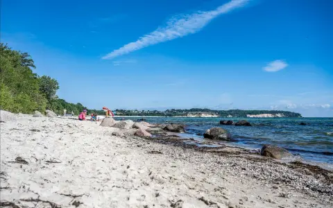 Kinder spielen am lobbe strand. Sand, Steine und das Meer bilden eine idyllische Szene unter blauem Himmel.