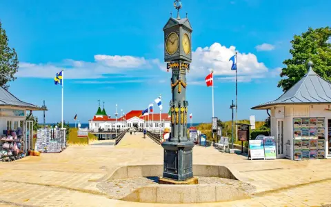 Prachtvoller Uhrenturm im Ahlbeck Zentrum, flankiert von Souvenirbuden und wehenden Flaggen.