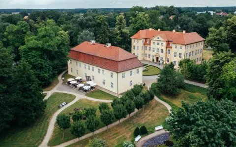 Zwei gelbe Barockschlösser mit roten Dächern auf der Schlossinsel Mirow, umgeben von üppigem Grün und gepflegten Wegen.