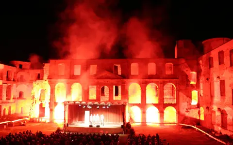 Spektakuläre Inszenierung im Schloss Dargun: Eine Bühne vor der Ruine, beleuchtet von rotem Licht und Nebel, lockt ein großes Publikum zu den Veranstaltungen.