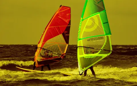 Zwei Windsurfer mit bunten Segeln auf dem Meer. Ein tolles Erlebnis für Surf und Segel Hiddensee.