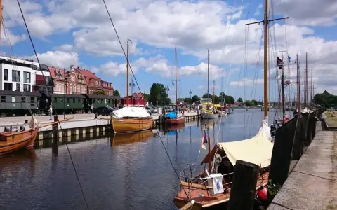 Boote im Greifswald Hafen liegen neben historischen Zügen.