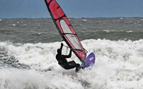 Windsurferin in Aktion auf der Ostsee, die mit ihrem Segel über die Wellen springt.