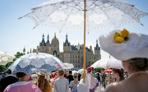 Besucher im historischen Gewand mit Sonnenschirmen beim Altstadtfest Schwerin vor dem Schloss.
