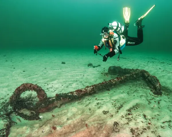 Taucher erkundet ein altes Ankerwrack in der Ostsee.