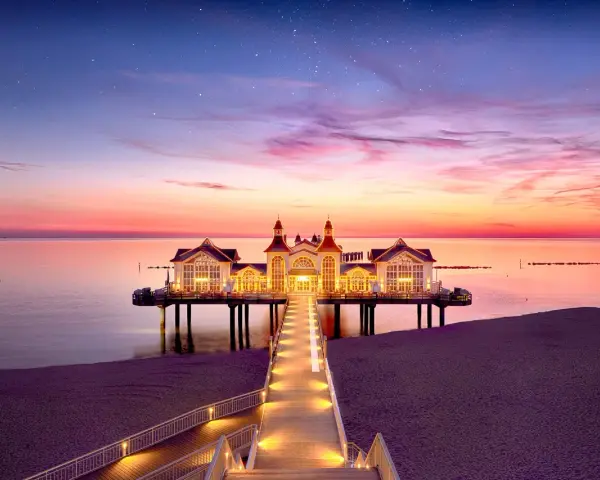 Pier mit beleuchtetem Gebäude im Abendrot, ein romantischer Blick auf die Sellin Innenstadt.