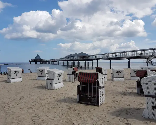 Strandkörbe am Zirchow Strand, mit Seebrücke und Wolkenhimmel.