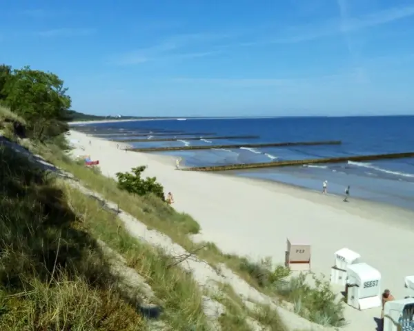Sonniger Strand Zempin mit Dünen, Wellenbrechern und Strandkörben.