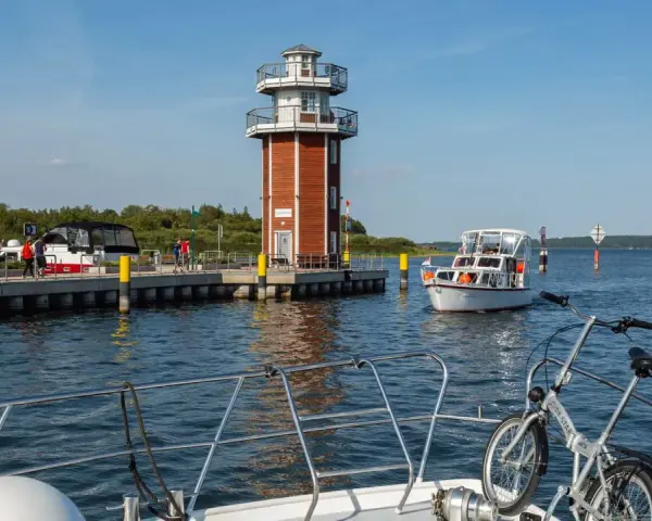 Plau am See: Leuchtturm und Promenade mit Booten. Ein Fahrrad wartet auf dem Vorderdeck.