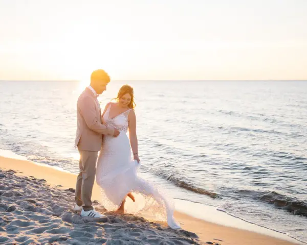 Ein glückliches Brautpaar feiert seine Hochzeit am Strand. Die Sonne geht unter und taucht die Szene in warmes Licht.