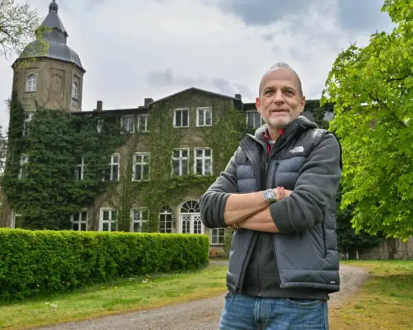 Mann vor dem historischen Gutshaus Wesselstorf, das von Efeu umrankt ist.