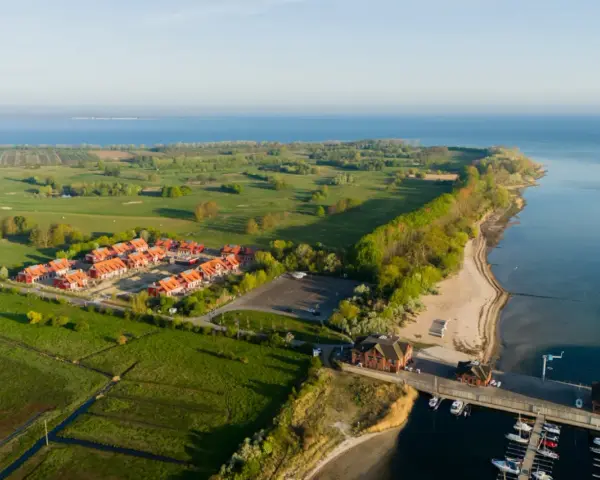 Ferienhäuser am Meer, daneben ein Golfplatz. Ein kleiner Hafen mit Booten.