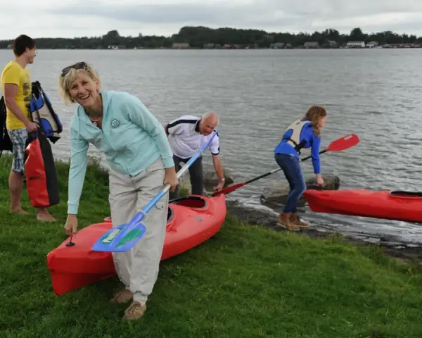 Familie bereitet sich auf einen Aktivurlaub an der Ostsee vor, holt Kajaks und Paddel aus dem Wasser.