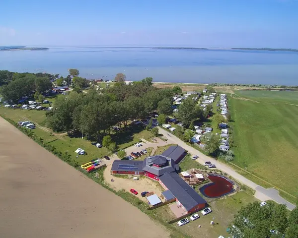 Luftaufnahme des pepelow campingplatzes mit Wohnmobilen, Bäumen und einem See im Hintergrund.