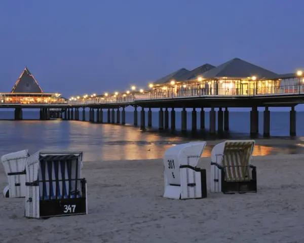 Strandkörbe am Abend vor der beleuchteten Seebrücke in Heringsdorf. Ein perfekter Ort für Geheimtipps am Meer.