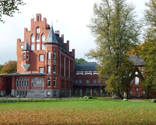 Das imposante Schloss Kalkhorst, ein Backsteinbau mit Türmchen und Erkern, steht im Herbstlicht.