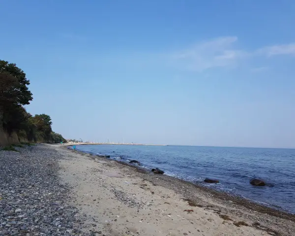 Ein ruhiger Tag am Wittenbeck Strand. Kies und Sand treffen auf das sanfte Meer, im Hintergrund eine Marina.