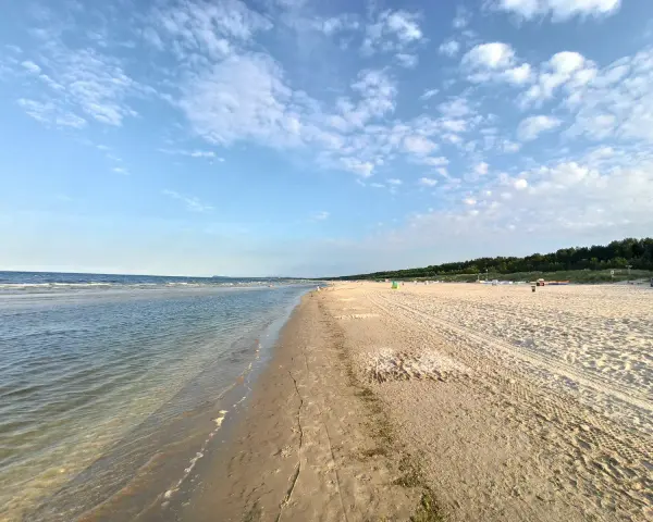 Sonniger Karlshagen Strand mit sanften Wellen und weitem Sand. Ein perfekter Ort für entspannte Tage am Meer.